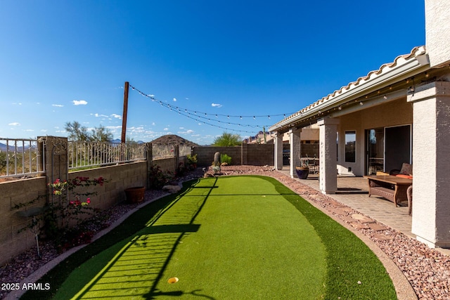 fenced backyard with a putting green and a patio