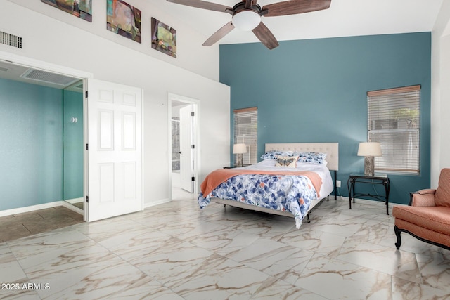 bedroom with a towering ceiling, marble finish flooring, baseboards, a ceiling fan, and connected bathroom