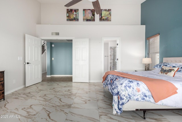 bedroom featuring a high ceiling, marble finish floors, baseboards, ensuite bath, and a ceiling fan