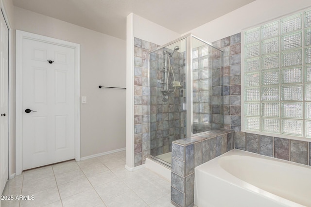 full bathroom featuring a stall shower, tile patterned flooring, a garden tub, and baseboards