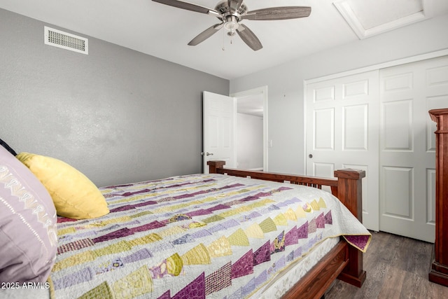 bedroom featuring dark wood finished floors, a closet, attic access, and a ceiling fan
