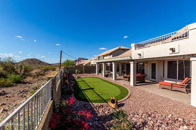 back of house with a putting area, a patio area, a fenced backyard, outdoor lounge area, and a mountain view
