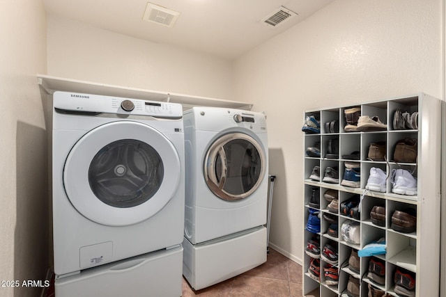 laundry area featuring separate washer and dryer, tile patterned floors, and baseboards