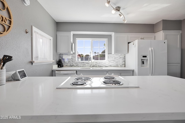 kitchen featuring white appliances, white cabinetry, a sink, and backsplash