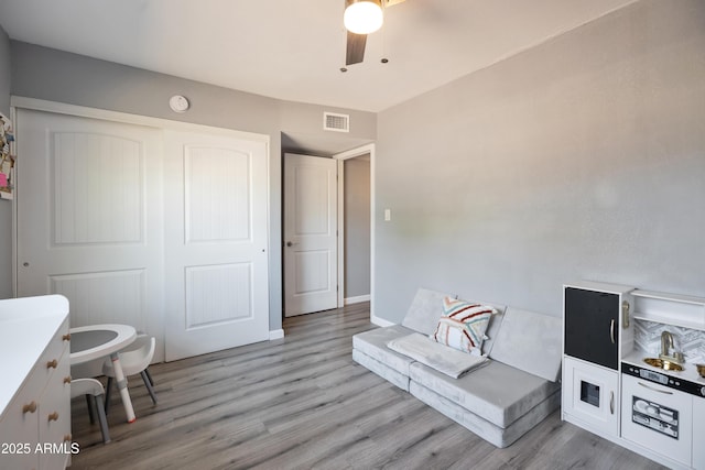 sitting room with light wood-style floors, visible vents, baseboards, and a ceiling fan