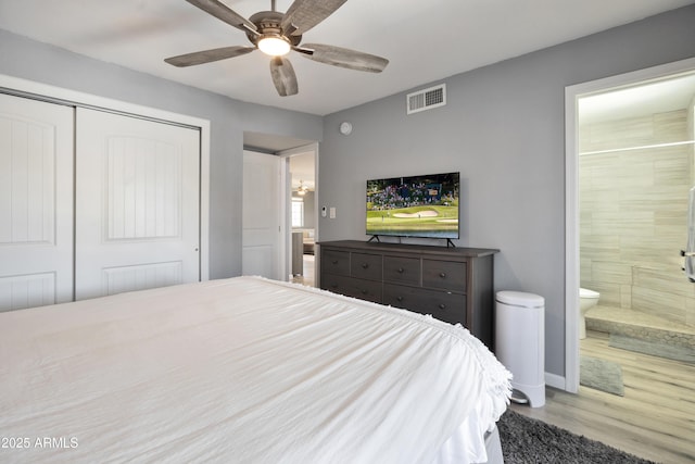 bedroom featuring connected bathroom, a closet, a ceiling fan, visible vents, and wood finished floors