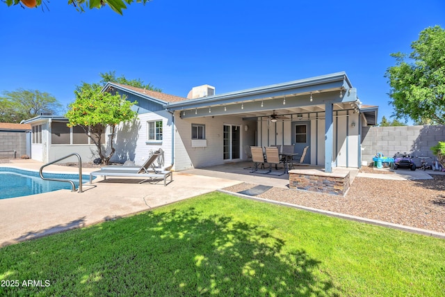back of house featuring a yard, a ceiling fan, a patio area, fence, and a fenced in pool