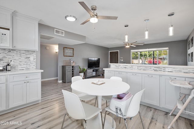 dining area with light wood-style flooring, ceiling fan, and visible vents