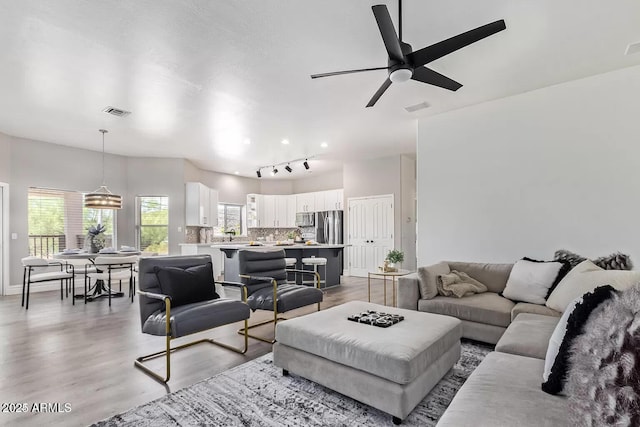 living area featuring light wood-style flooring, visible vents, and a ceiling fan