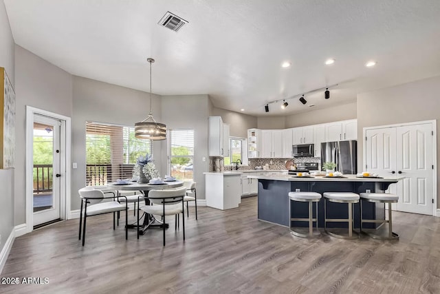 kitchen featuring light countertops, a kitchen island, white cabinetry, stainless steel appliances, and decorative backsplash