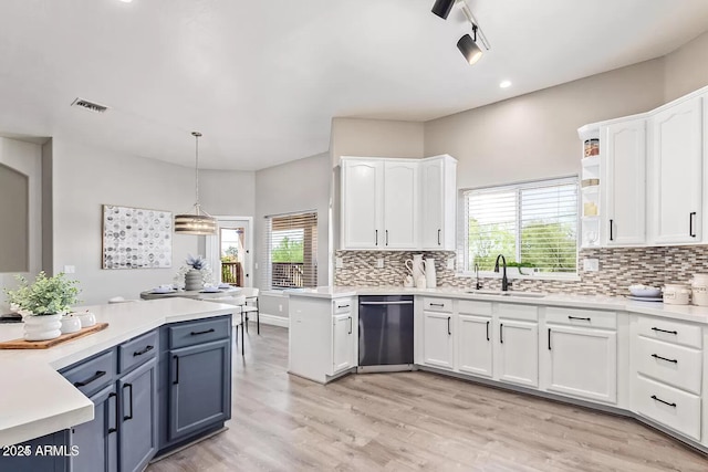 kitchen with a sink, white cabinetry, tasteful backsplash, light wood-style flooring, and visible vents