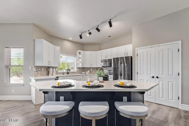 kitchen featuring white cabinetry, light countertops, appliances with stainless steel finishes, and backsplash