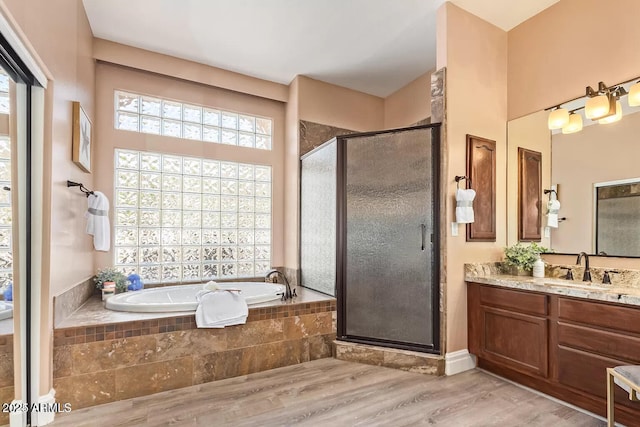 full bathroom featuring wood finished floors, vanity, a garden tub, and a shower stall