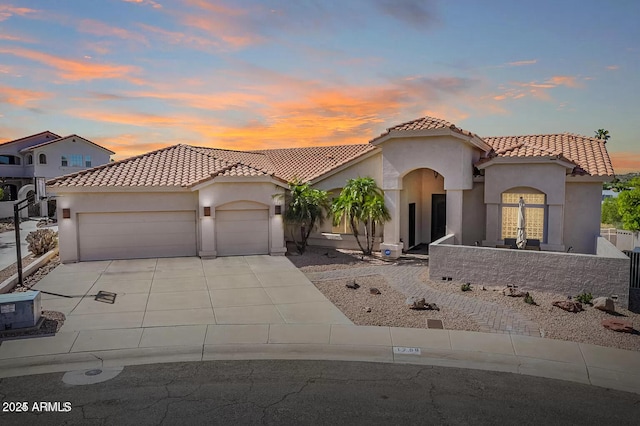 mediterranean / spanish house with a tile roof, concrete driveway, stucco siding, and an attached garage