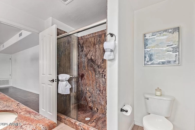 bathroom featuring toilet, vanity, a stall shower, and baseboards