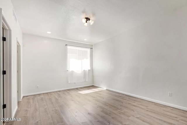 spare room with baseboards, wood finished floors, and recessed lighting