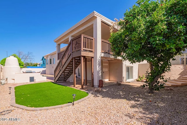 rear view of property featuring fence, stucco siding, stairs, and a patio