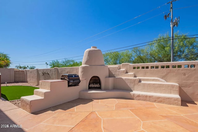 view of patio with a fenced backyard, area for grilling, and an outdoor fireplace