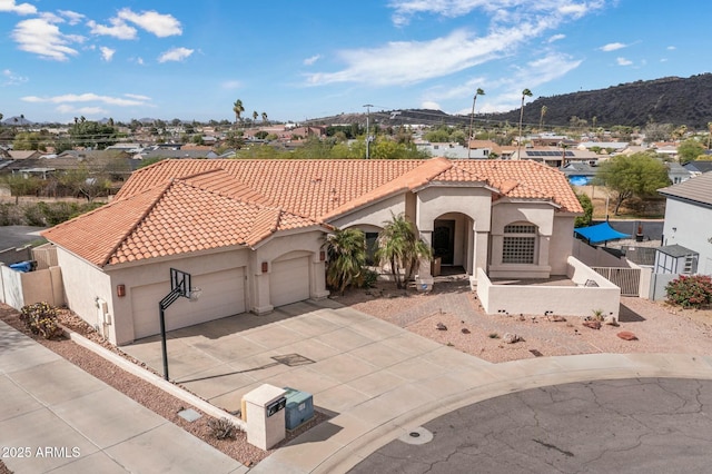 mediterranean / spanish-style house with stucco siding, a tile roof, a garage, and driveway