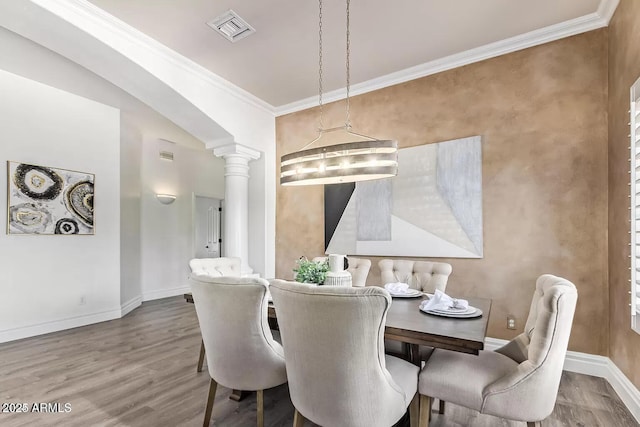 dining room featuring visible vents, crown molding, baseboards, ornate columns, and wood finished floors