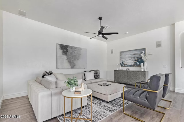 living room with a ceiling fan, baseboards, and wood finished floors