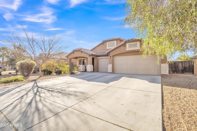 mediterranean / spanish-style home with a garage, driveway, a tiled roof, and stucco siding