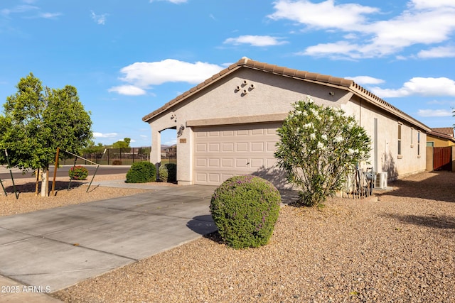 7305 W Darrel Rd, Laveen, AZ 85339 - view of home's exterior featuring a garage, central AC, stucco siding, driveway, and a tile roof