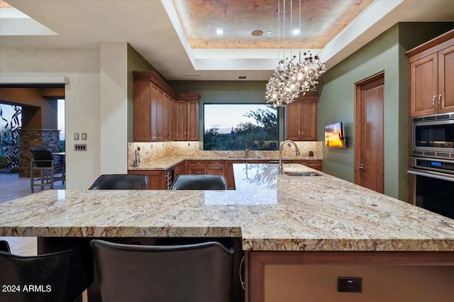 kitchen featuring sink, stainless steel appliances, backsplash, pendant lighting, and a breakfast bar area