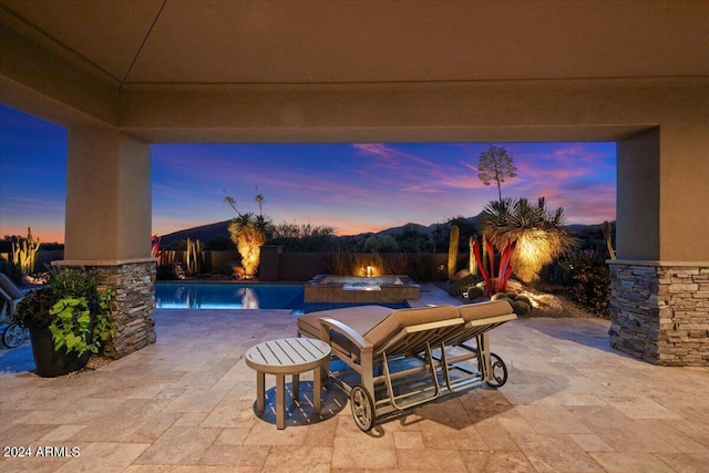 patio terrace at dusk featuring pool water feature and a pool with hot tub