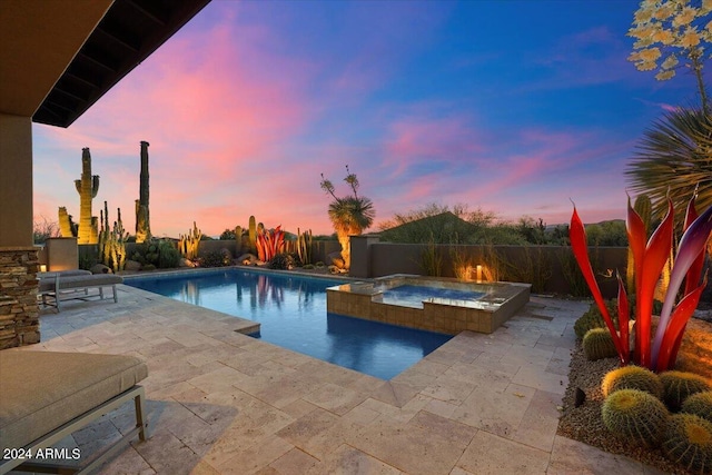 pool at dusk with a patio area and an in ground hot tub