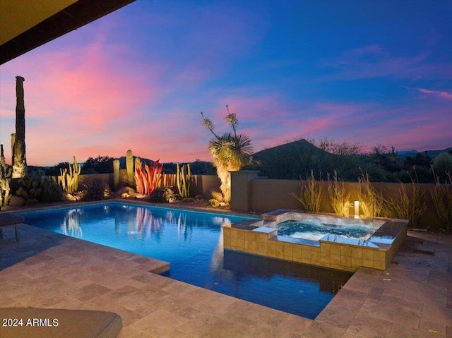 pool at dusk with an in ground hot tub