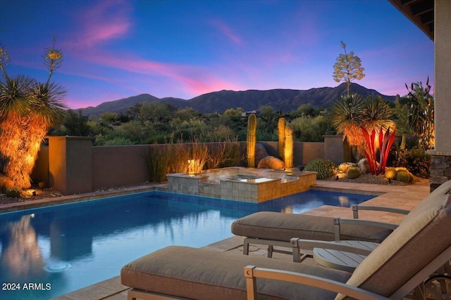 pool at dusk with an in ground hot tub and a mountain view