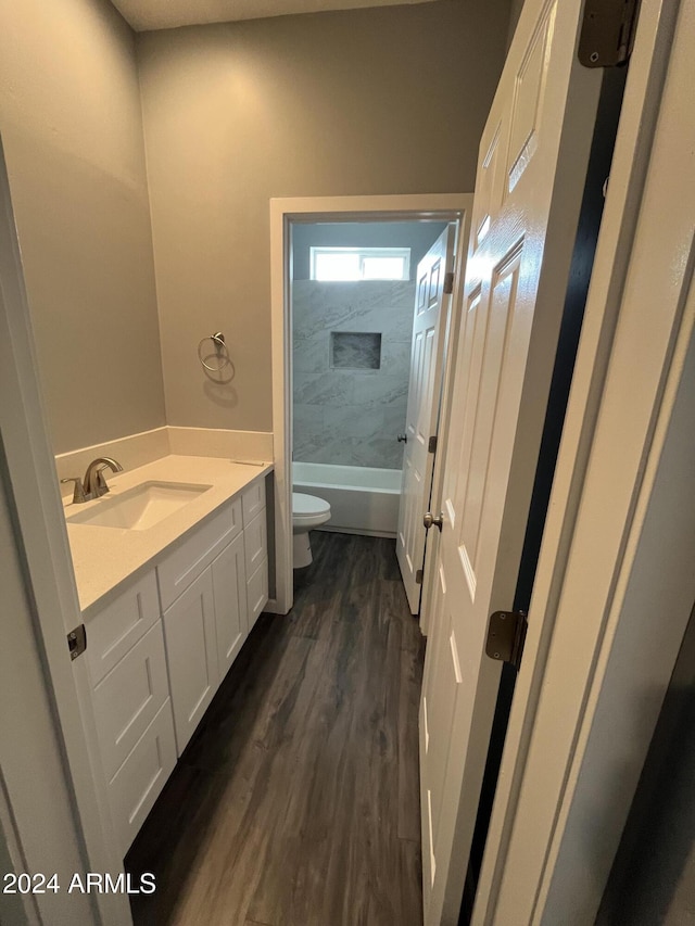 full bathroom with tiled shower / bath, vanity, wood-type flooring, and toilet