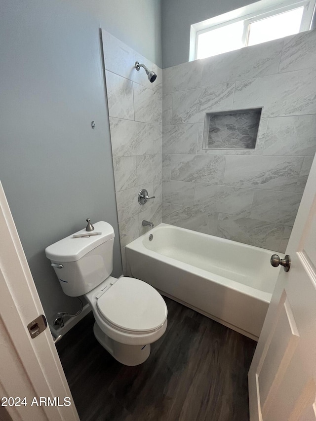 bathroom featuring toilet, wood-type flooring, and tiled shower / bath