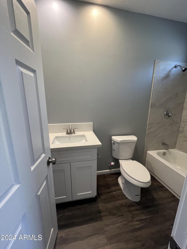 full bathroom featuring vanity, wood-type flooring, tiled shower / bath combo, and toilet