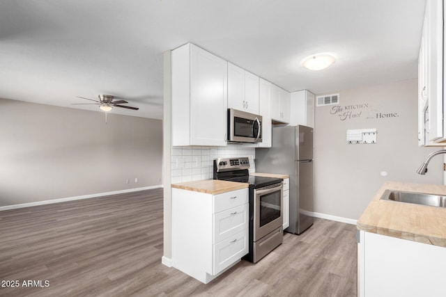 kitchen with sink, white cabinets, stainless steel appliances, and tasteful backsplash