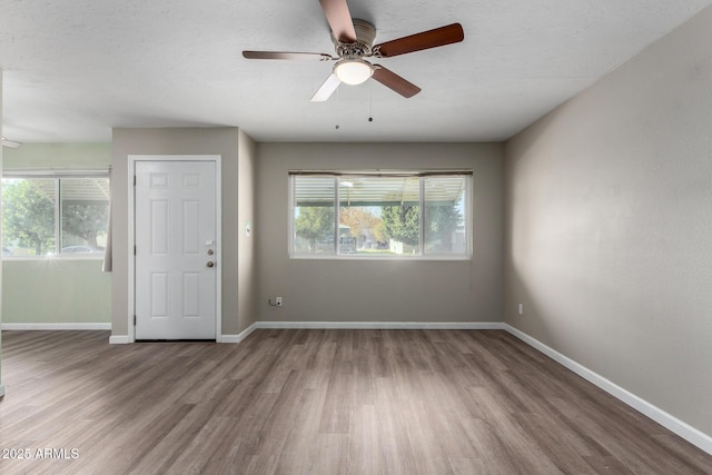 unfurnished room with ceiling fan, wood-type flooring, and a wealth of natural light