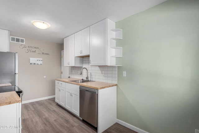 kitchen with tasteful backsplash, white cabinets, appliances with stainless steel finishes, and sink