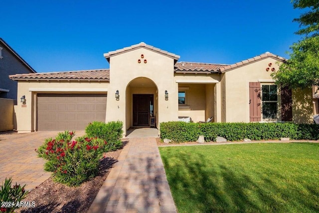 mediterranean / spanish home with a garage and a front lawn