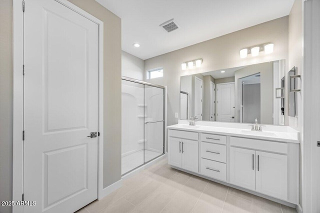 bathroom with double vanity, a shower stall, visible vents, and a sink