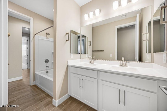 full bath with double vanity, wood finish floors, tub / shower combination, and a sink