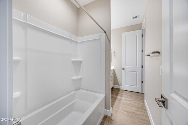 full bathroom with shower / washtub combination, wood finish floors, visible vents, and baseboards