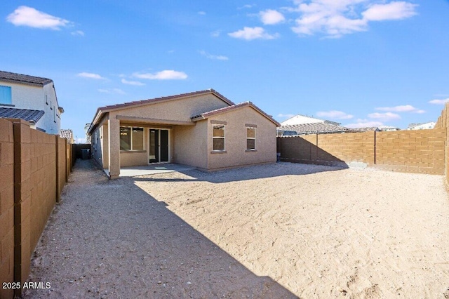 back of house with a fenced backyard, a patio, a tiled roof, and stucco siding