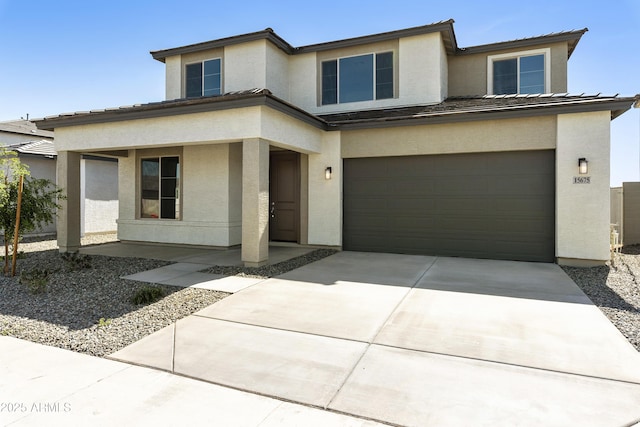 prairie-style home featuring concrete driveway, an attached garage, a tile roof, and stucco siding