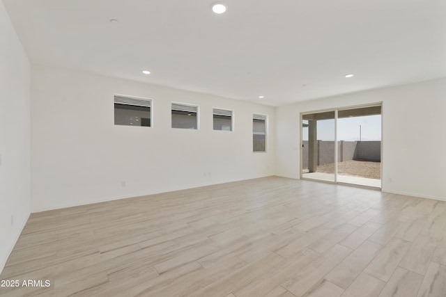empty room with baseboards, recessed lighting, and light wood-style floors
