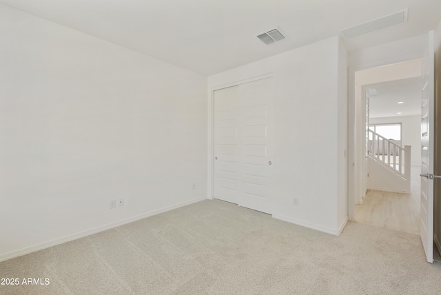 spare room with carpet, visible vents, and baseboards