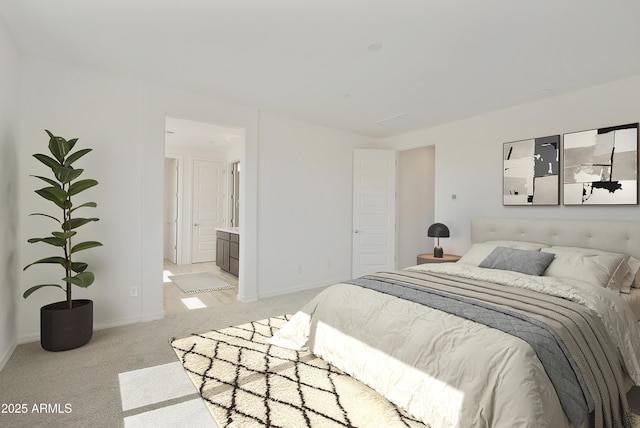 bedroom featuring light carpet, ensuite bath, and baseboards