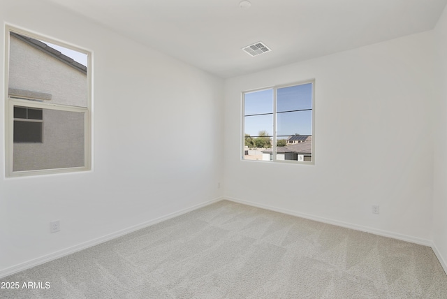 empty room with carpet, visible vents, and baseboards