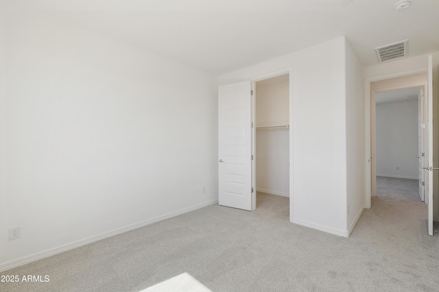 unfurnished bedroom featuring carpet, a walk in closet, visible vents, and baseboards