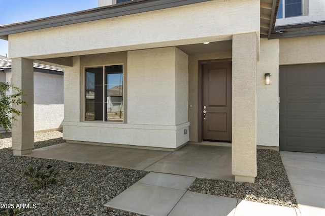 entrance to property featuring a garage and stucco siding